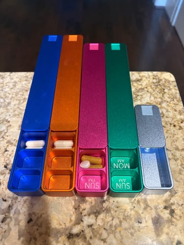 Customer's colorful collection of metal Weekly AM-PM Pill Cases. Several are open, showing pills in their compartments.
