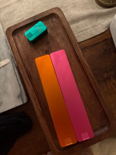 Customer's orange, pink, and teal Weekly AM-PM Vitamin Cases displayed on a wooden tray.
