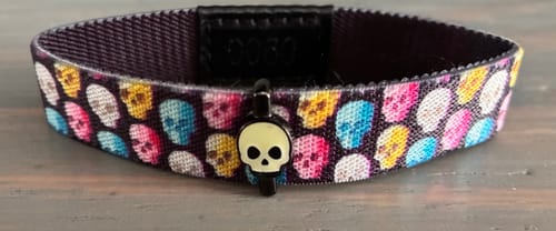 Customer's Glow-In-The-Dark Skull Charm on a colorful skull-patterned bracelet.