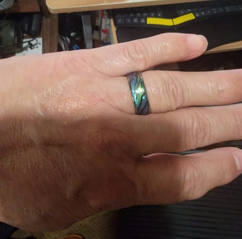 Customer wearing the Nerium ring, showing its polished band and iridescent inlay.
