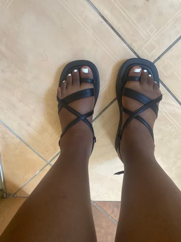 A reviewer's overhead view of their feet in the black, strappy Viabeach Coconut 21 Sandals.