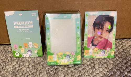 Reviewer displays the PREMIUM FRAME SLEEVES packaging, an empty sleeve, and one holding a photocard.