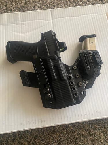 Customer's black APX holster with a carbon fiber pattern, holding a handgun and a spare magazine.
