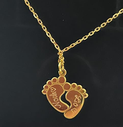 Kundenbild der gravierten, goldenen Halskette 'Babyfüßchen' mit den Namen 'Noah' und 'Lio'.