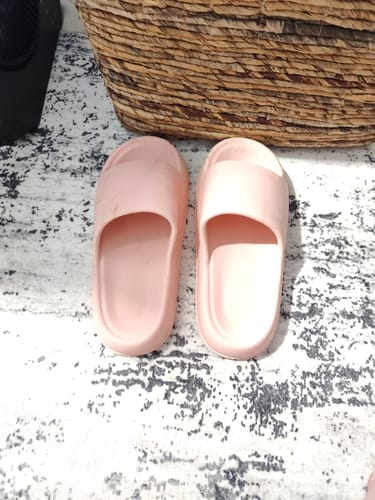 A customer's pink Cloud Slides on a patterned rug.