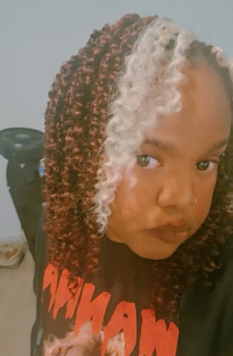 Customer's close-up of the reddish-brown Passion Twist braids, which they customized with a thick blonde front section.