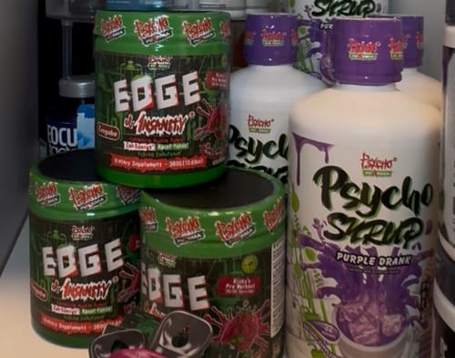 Customer's stacked green tubs of Edge of Insanity supplement on a shelf.