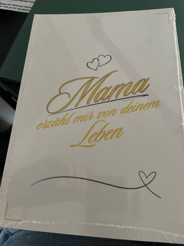 Kunde zeigt das neue Buch 'Mama, erzähl mir von deinem Leben' noch in der Plastikfolie.