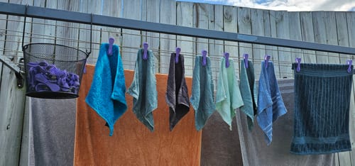 Customer's purple Hegs Pegs securely holding various towels on an outdoor clothesline.