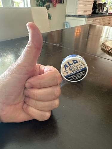 A customer gives a thumbs-up next to a can of ALP Chilled Mint Nicotine Pouches on a table.
