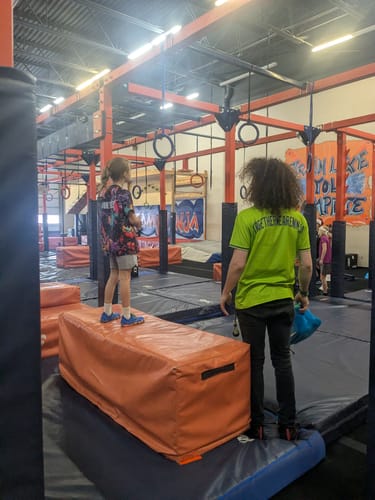Reviewer's photo of a child standing on an obstacle in a ninja gym, wearing the reviewed shoes.