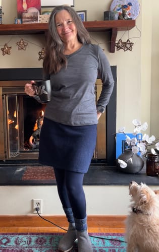 Reviewer wearing the long-sleeved Lily V Neck Lounge Top in grey, styled with a skirt and leggings indoors.
