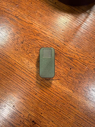Customer's dark green Nano Case shown closed on a rich wood-grain table.