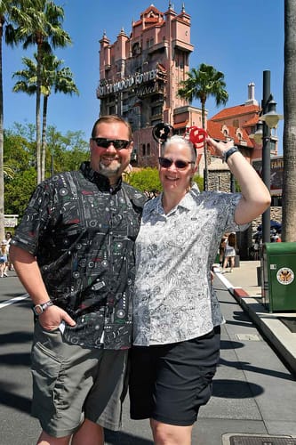 Customer wearing the black 'Saber Schematics' KUNUFLEX Short Sleeve Shirt while posing at a theme park.