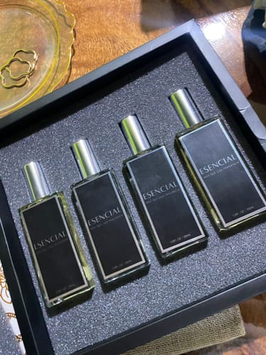 Cliente muestra cuatro perfumes ESENCIAL en una caja negra de presentación.