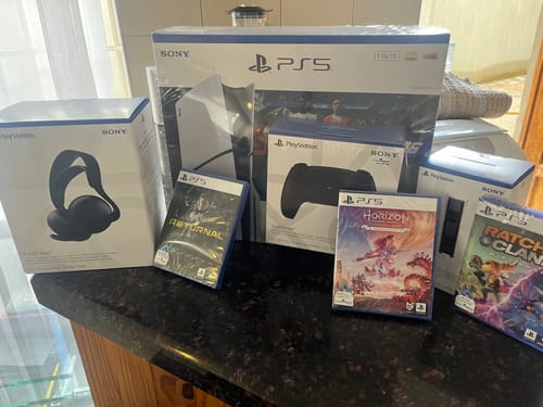 Customer's new PS5 console, controller, headset, and several games displayed in their boxes on a counter.