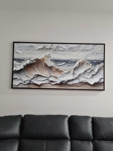 Customer's large, framed Ocean Waves Wall Art hanging on a wall above a dark leather couch.