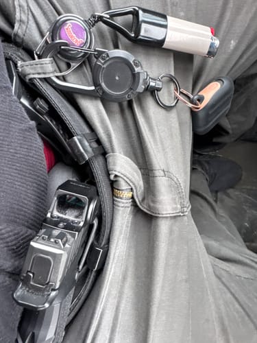 Close-up of a reviewer's APX holster worn for appendix carry inside their grey pants, with a handgun secured.