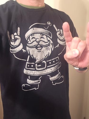 Customer wearing the black El Rocker Santa Clause t-shirt while making a rock-on hand gesture.