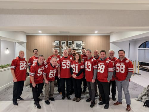 Customers wearing their custom burgundy football jerseys for a group photo indoors.
