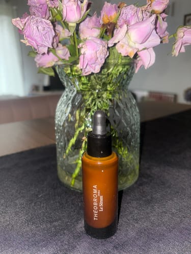 Le Sérum (TH3+) d'un client, posé sur une table devant un vase de fleurs.