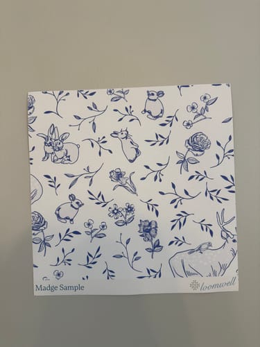 Customer's sample of the Madge Wallpaper showing a blue and white pattern with rabbits, deer, and flowers.