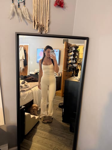 Reviewer wearing the high-waisted, flared Leisure Pant in cream in a full-length mirror photo.