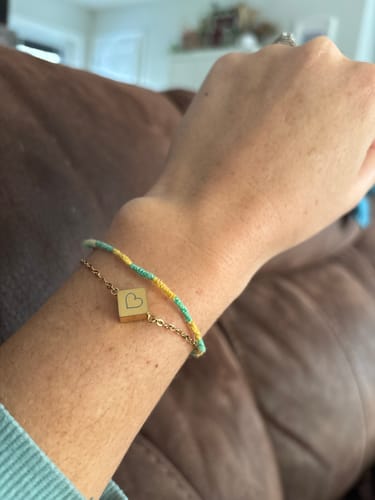 Customer wearing the dainty Diamond Square Urn Bracelet with a heart charm on their wrist.