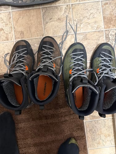 Reviewer's two pairs of Crispi Altitude GTX boots, one brown and one green, shown side-by-side on a floor.