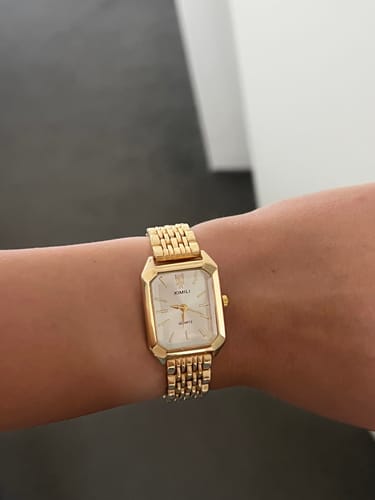 Reviewer showing their gold CLAIRE DE MAINS watch with a white face on their wrist.