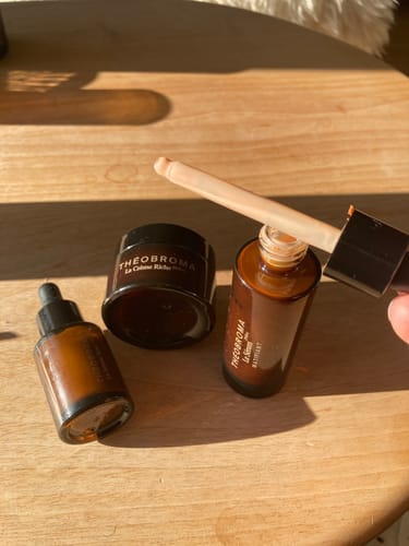 Photo d'un client montrant la texture rosée du Sérum Matifiant sur la pipette, posé à côté d'autres produits.