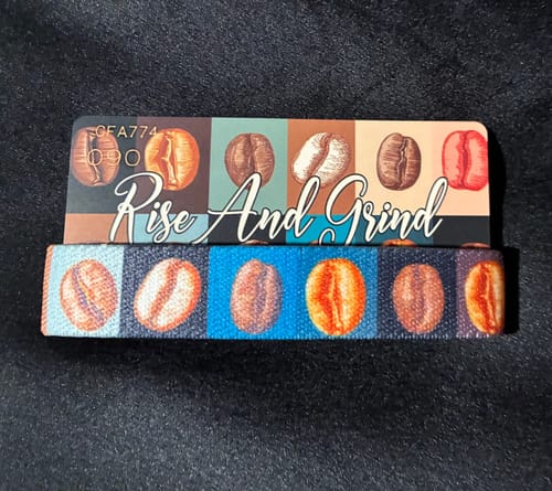 Reviewer's 'Rise And Grind' wristband from the Coffee Collection, showing its colorful coffee bean design and matching card.