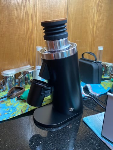 Customer's black DF64 gen2 coffee grinder with dosing cup, placed on a kitchen counter.