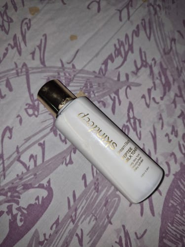 Customer's DREAM GLAZE - Peptide Milk Toner bottle with its gold cap, resting on a patterned background.