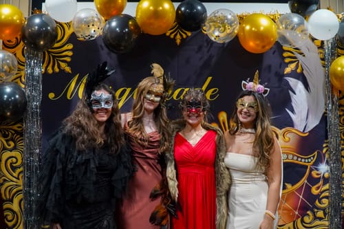 Reviewer and guests in ornate masks and dresses at their Masquerade Murder Mystery party.