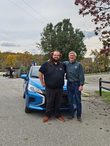 Customer standing with their shiny blue Mitsubishi Mirage, the car featured in their Flowgenix detailing spray review.