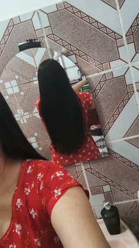 Avaliadora de costas mostrando seu cabelo preto e longo, resultado do tratamento com Happy Hair.