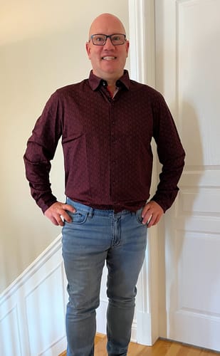 Client portant la chemise rouge NELUMBO avec un jean, les mains sur les hanches.