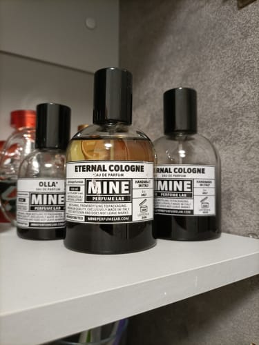 Recensore mostra i suoi flaconi di profumo ETERNAL COLOGNE su una mensola bianca.