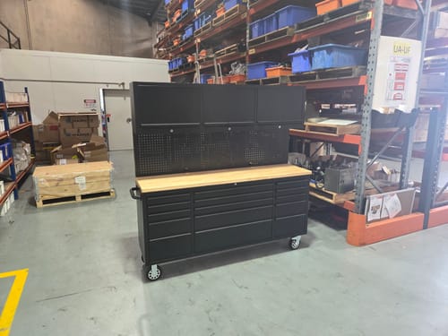 Reviewer's assembled black Workstation Cabinet with a wooden top and pegboard in a large warehouse.