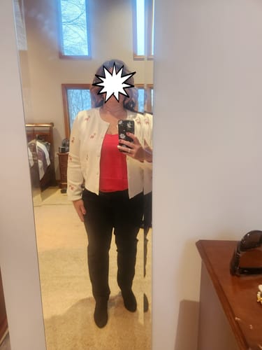 Reviewer in a mirror selfie wearing the cropped Baby Please Come Home Cardigan with a red top and black pants.