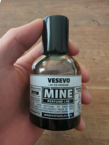 Un cliente tiene in mano la piccola boccetta scura dell'eau de parfum VESEVO.