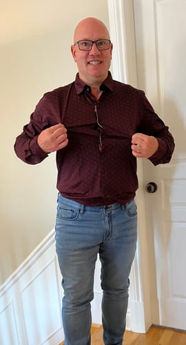 Client qui étire le tissu de sa chemise rouge NELUMBO pour en montrer l'élasticité.