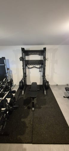 Rezensent zeigt das aufgebaute R8 Bradley Power Rack in einem Heimstudio mit einer Hantelbank.