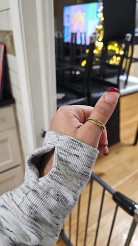 Customer's hand showing a gold stacked ring from the jewelry bundle worn on the thumb.