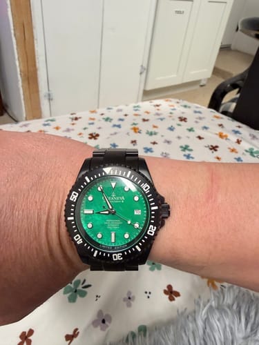 Customer's Oceaneva Deep Marine Explorer III watch with a green mother-of-pearl dial and black case, shown on their wrist.