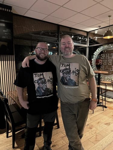 Reviewer and a friend wearing their custom-printed Unisex t-shirts, one black and one green.