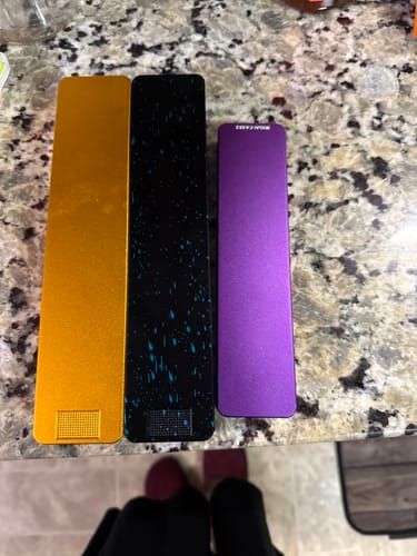 Customer's three colorful metal Vitamin XL Cases lined up on a granite countertop.