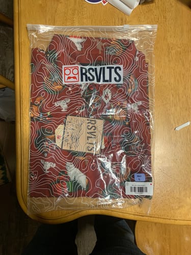 Customer's 'Christmas Critters' shirt folded inside its clear packaging on a wooden surface.