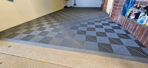 Customer's garage with installed modular interlocking flooring in a grey and black checkerboard pattern with edge pieces.